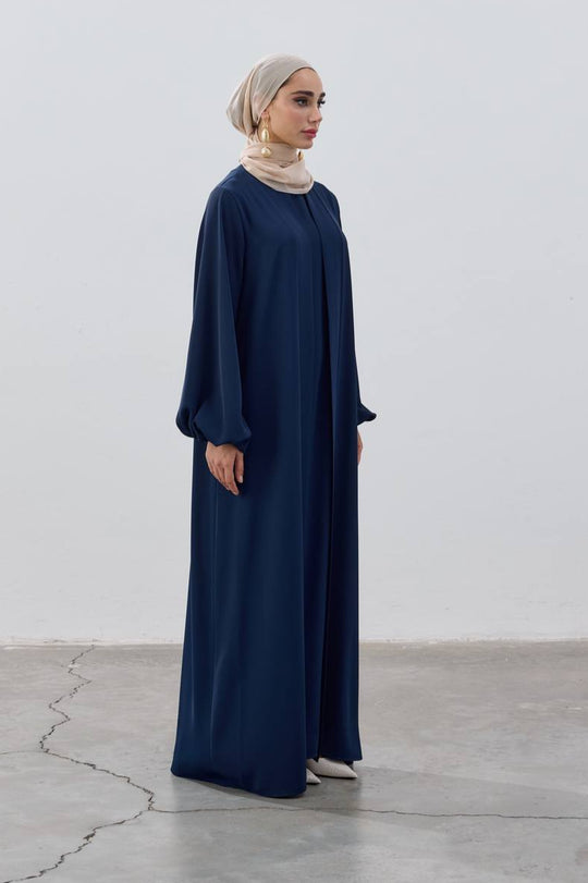 Woman wearing a long navy blue dress against a white background
