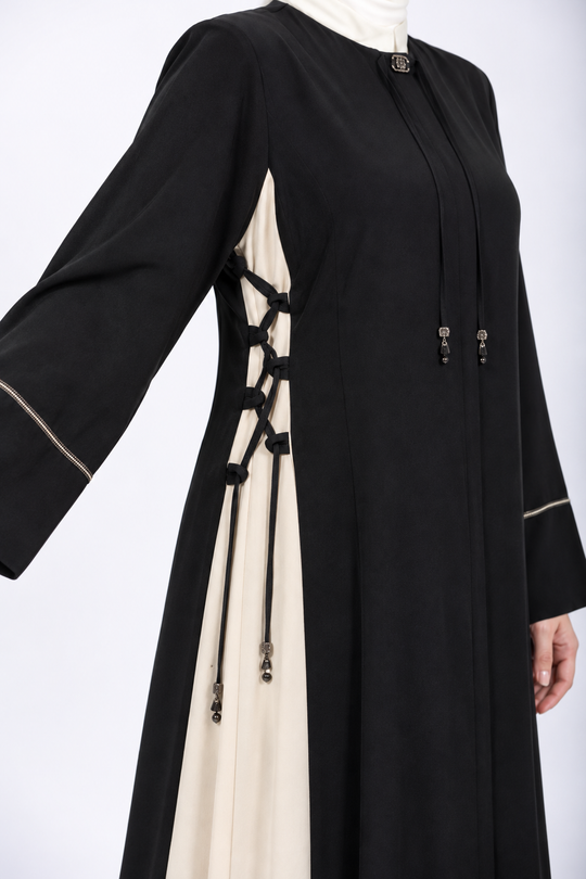 Close-up of side lace-up detail on black and cream abaya
