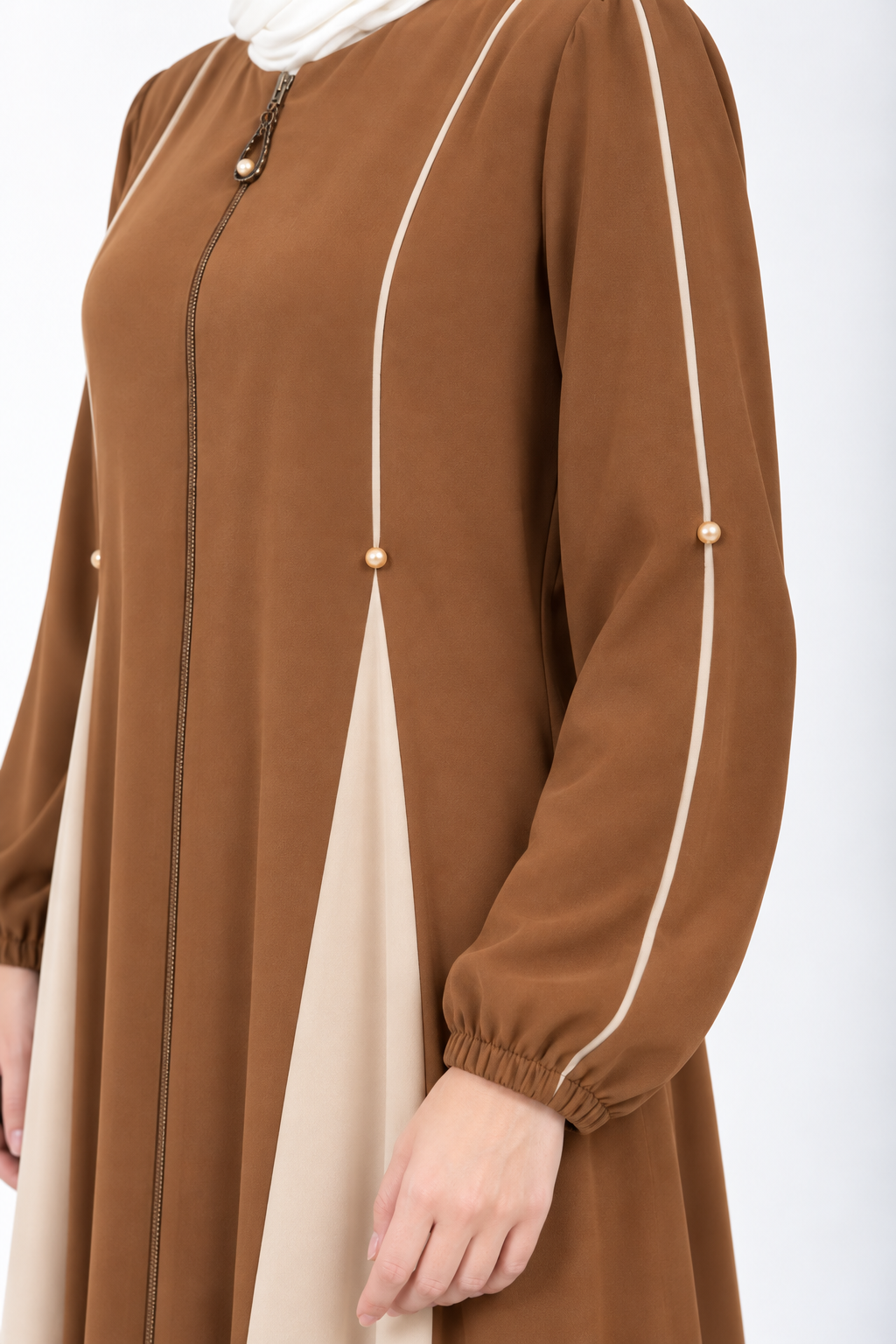 Close-up of cream piping and pearl accent on cumin abaya