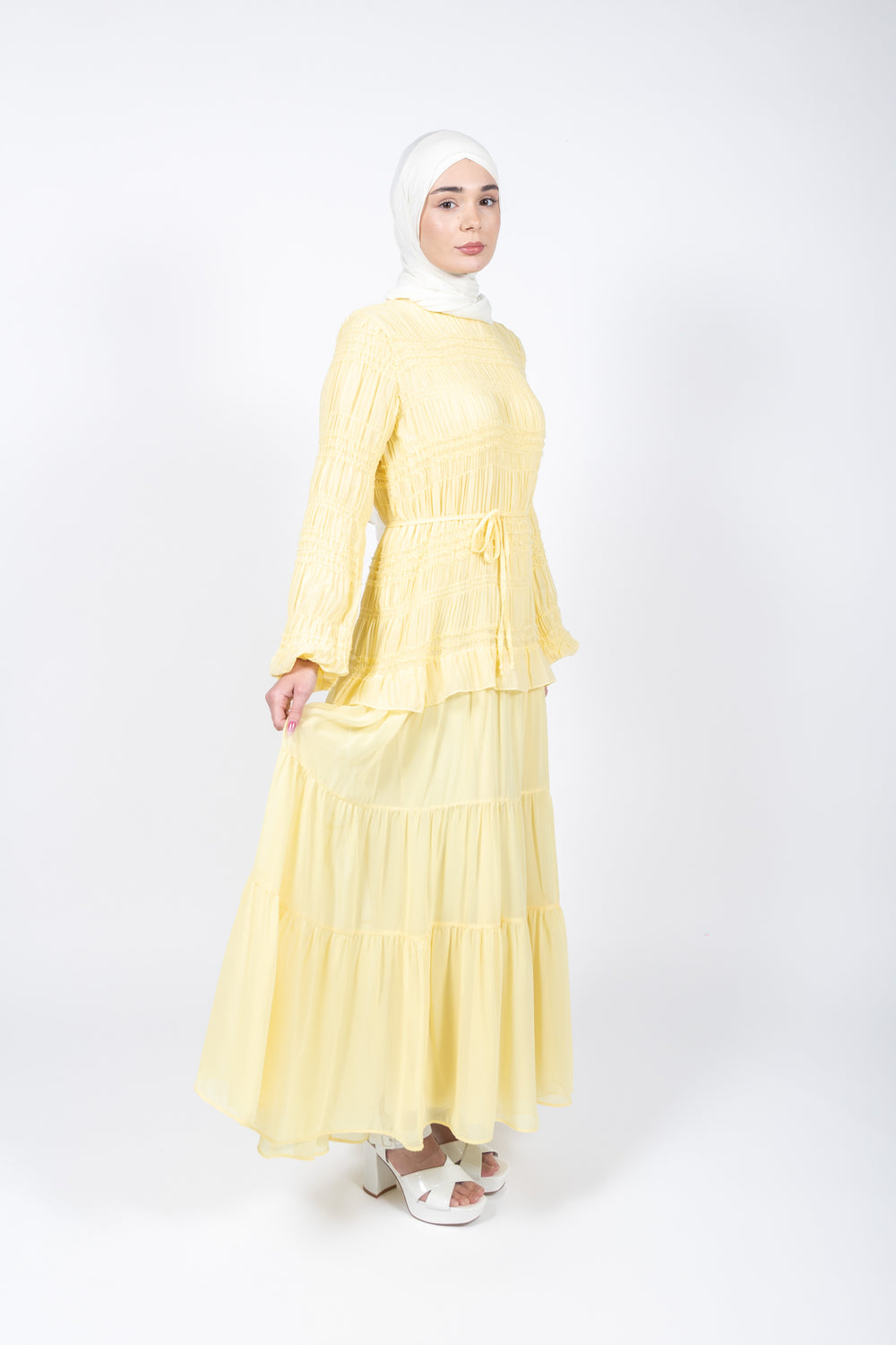 Woman wearing a yellow dress with a white hijab on a white background