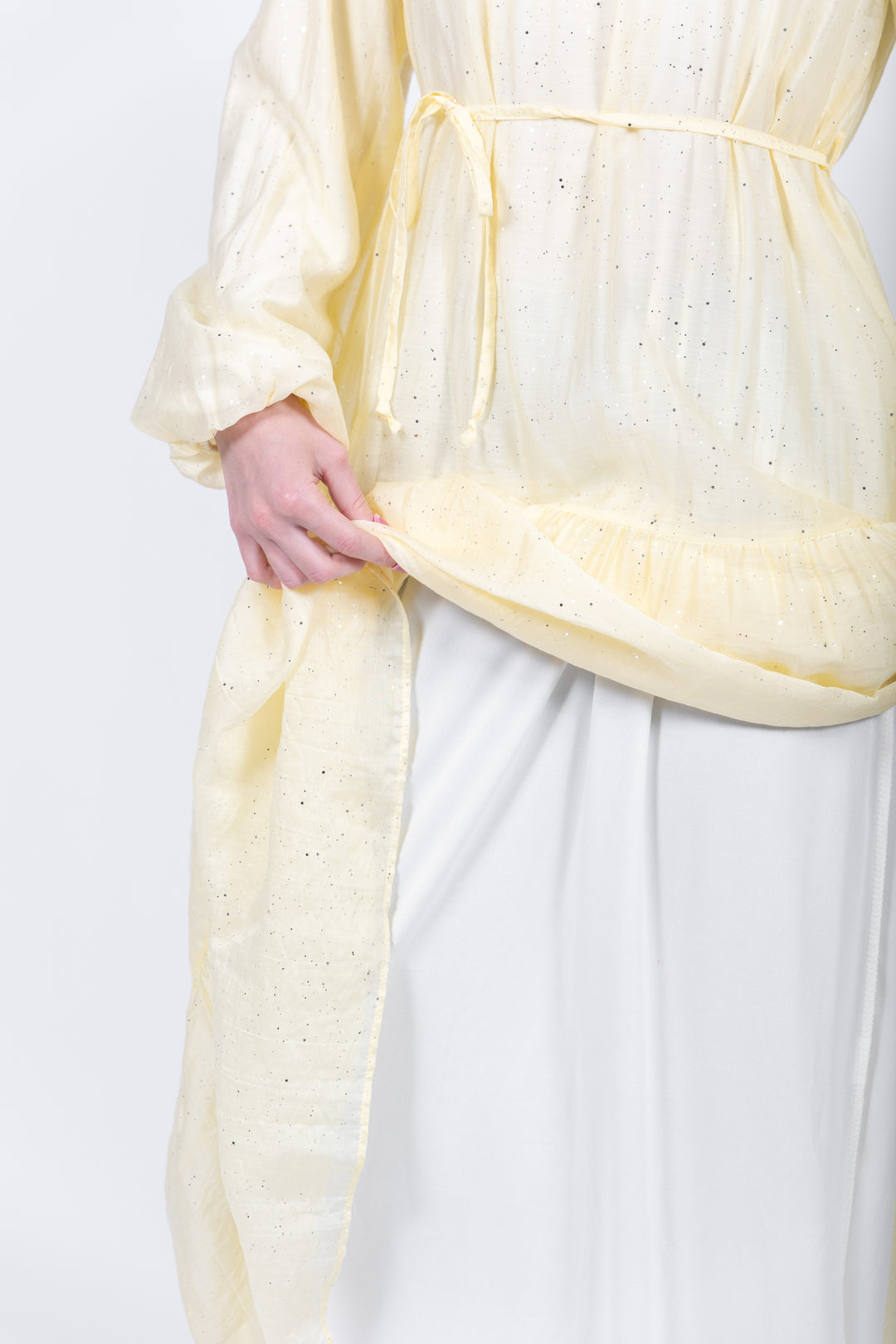 Person wearing a light yellow top with a white background