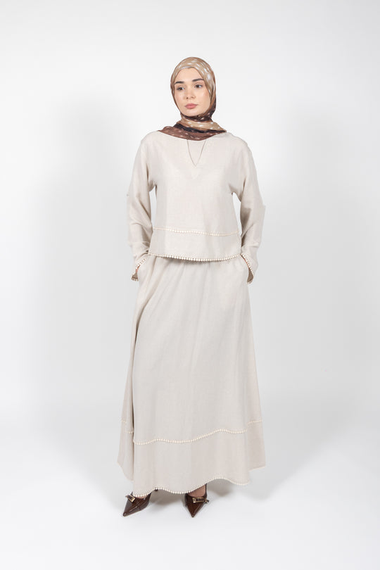 Woman wearing a beige outfit with a hijab on a white background