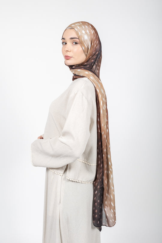 Woman wearing a beige hijab with a subtle pattern on a white background