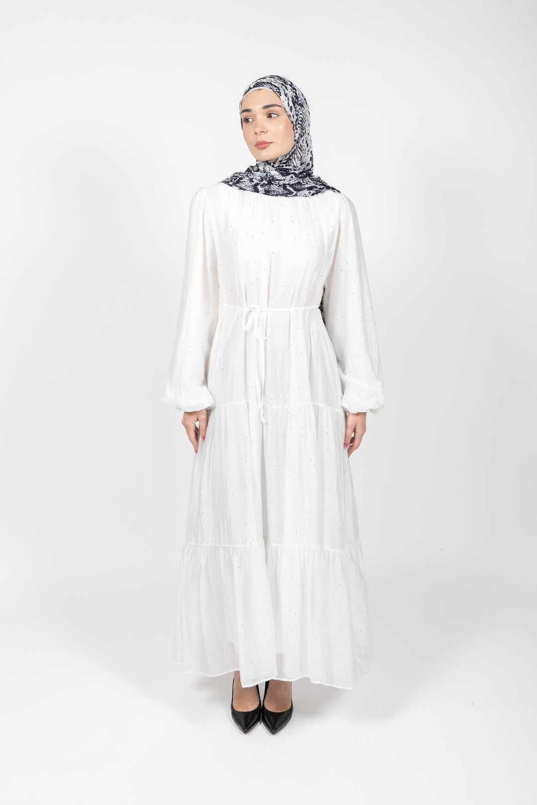 Woman wearing a white dress and patterned hijab on a white background