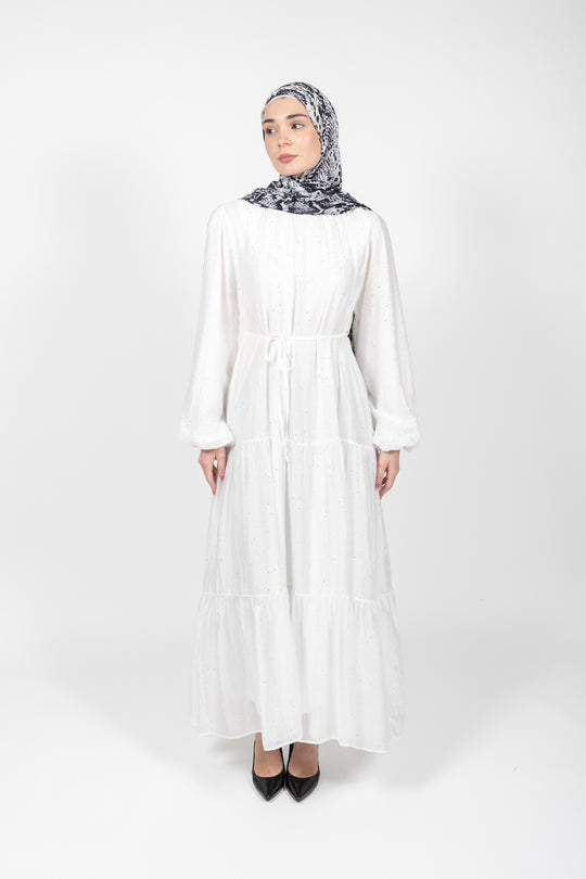 Woman wearing a white dress and patterned hijab on a white background