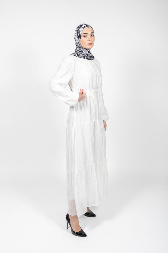 Woman wearing a white dress and patterned hijab on a white background
