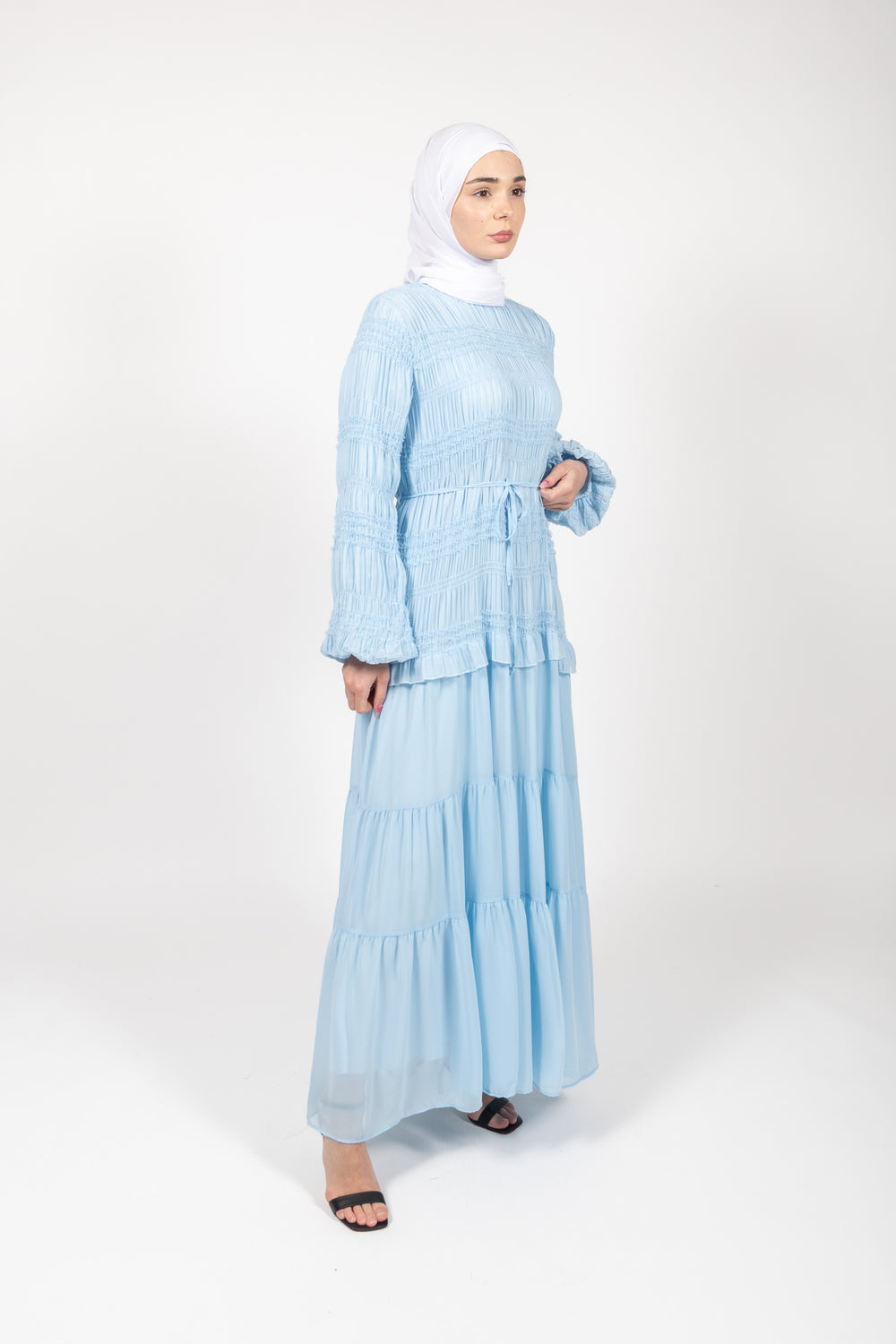 Woman wearing a light blue dress with a hijab on a white background