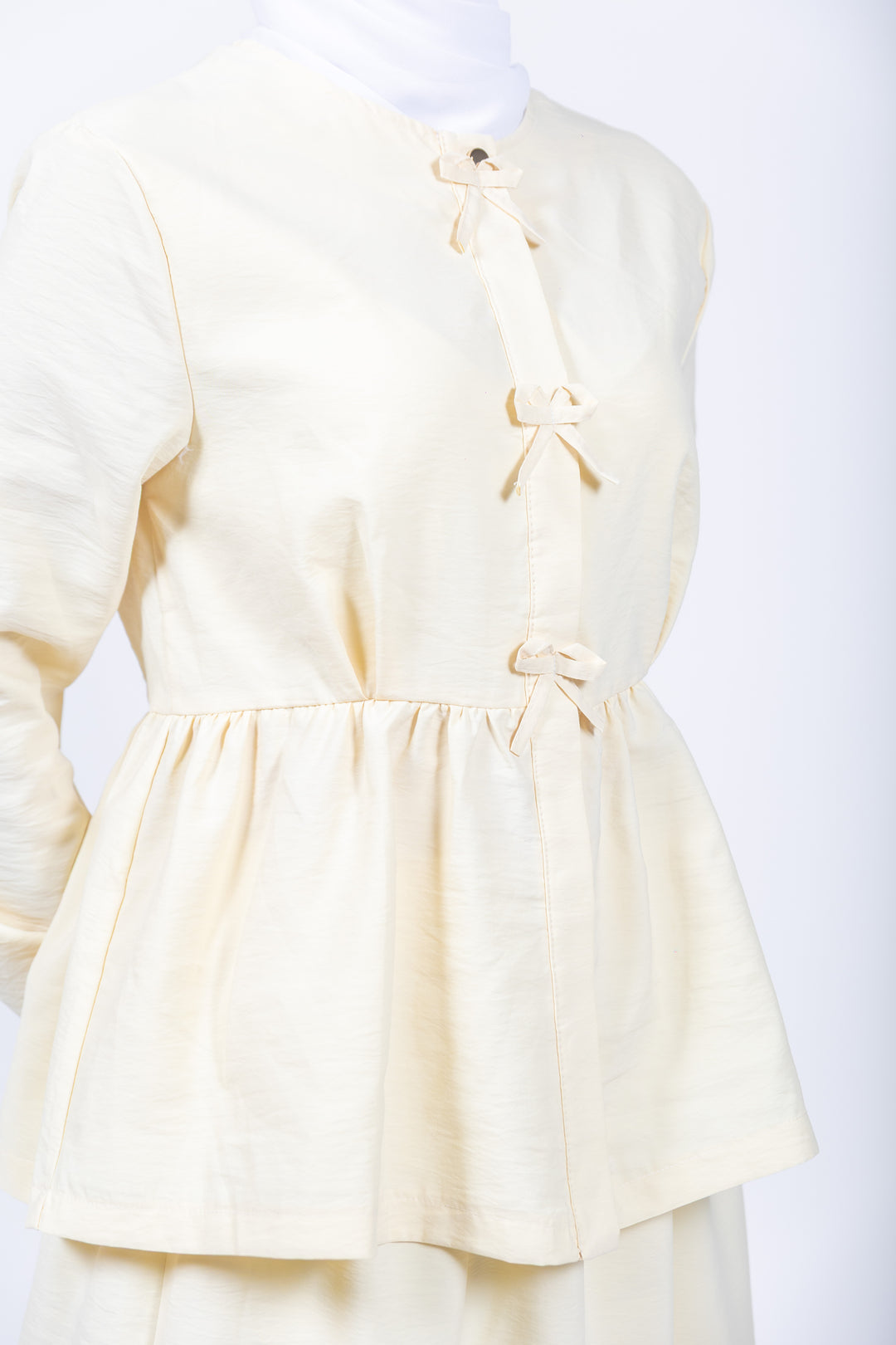 Light yellow dress with bow details on a white background