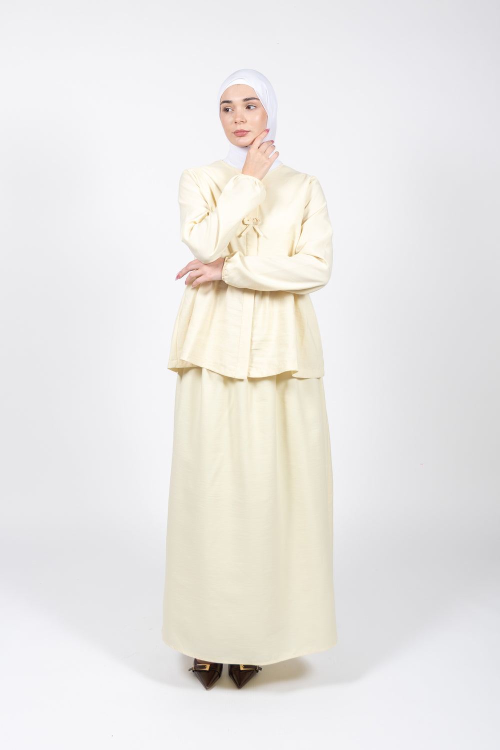 Woman wearing a cream-colored outfit with a matching hijab on a white background
