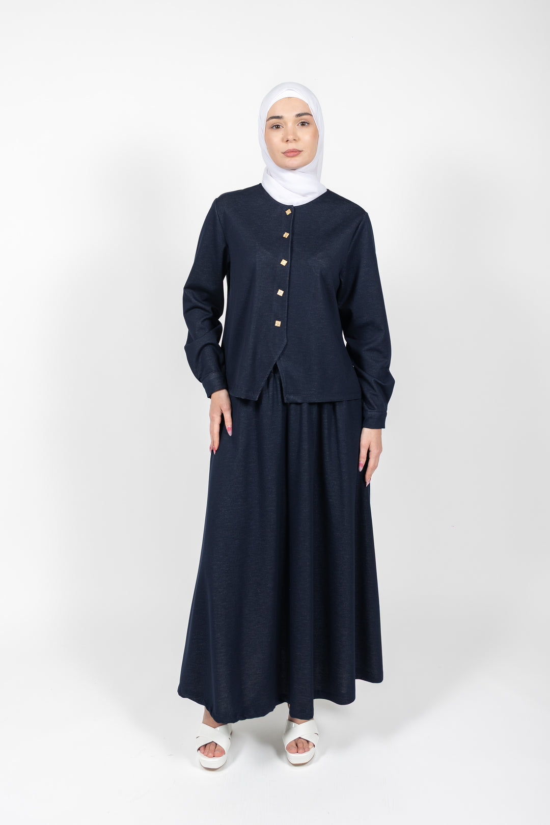 Woman wearing a navy blue outfit with a hijab on a white background