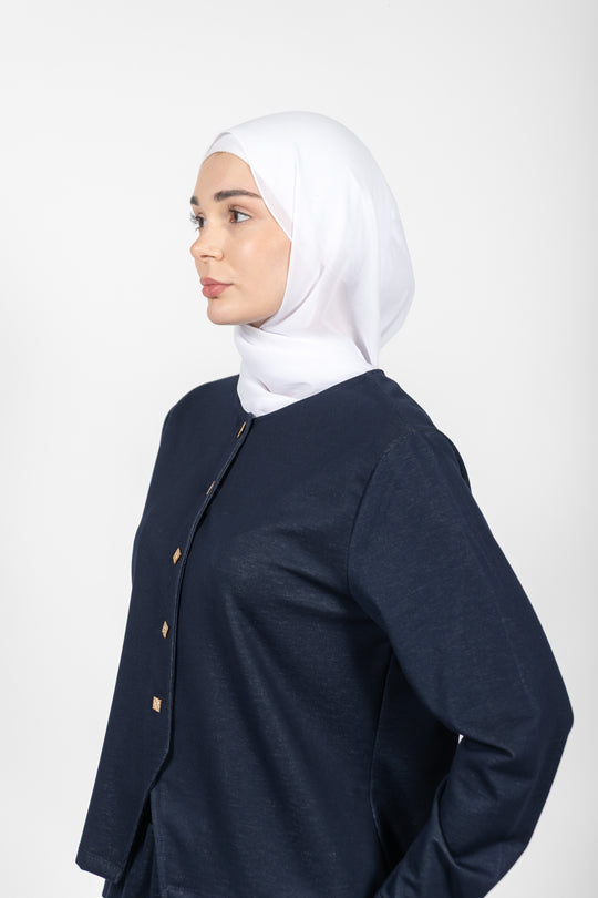 Woman wearing a navy blue jacket with gold buttons on a white background