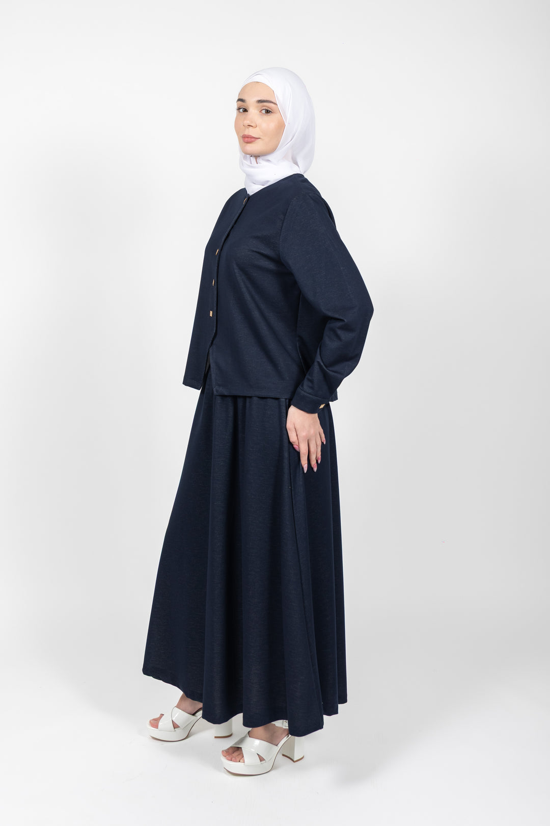 Woman wearing a navy blue outfit with a white hijab on a white background