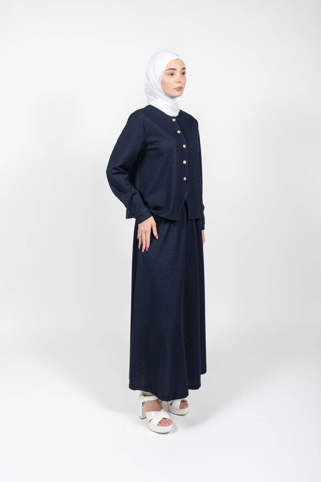 Woman wearing a navy blue outfit with a hijab on a white background