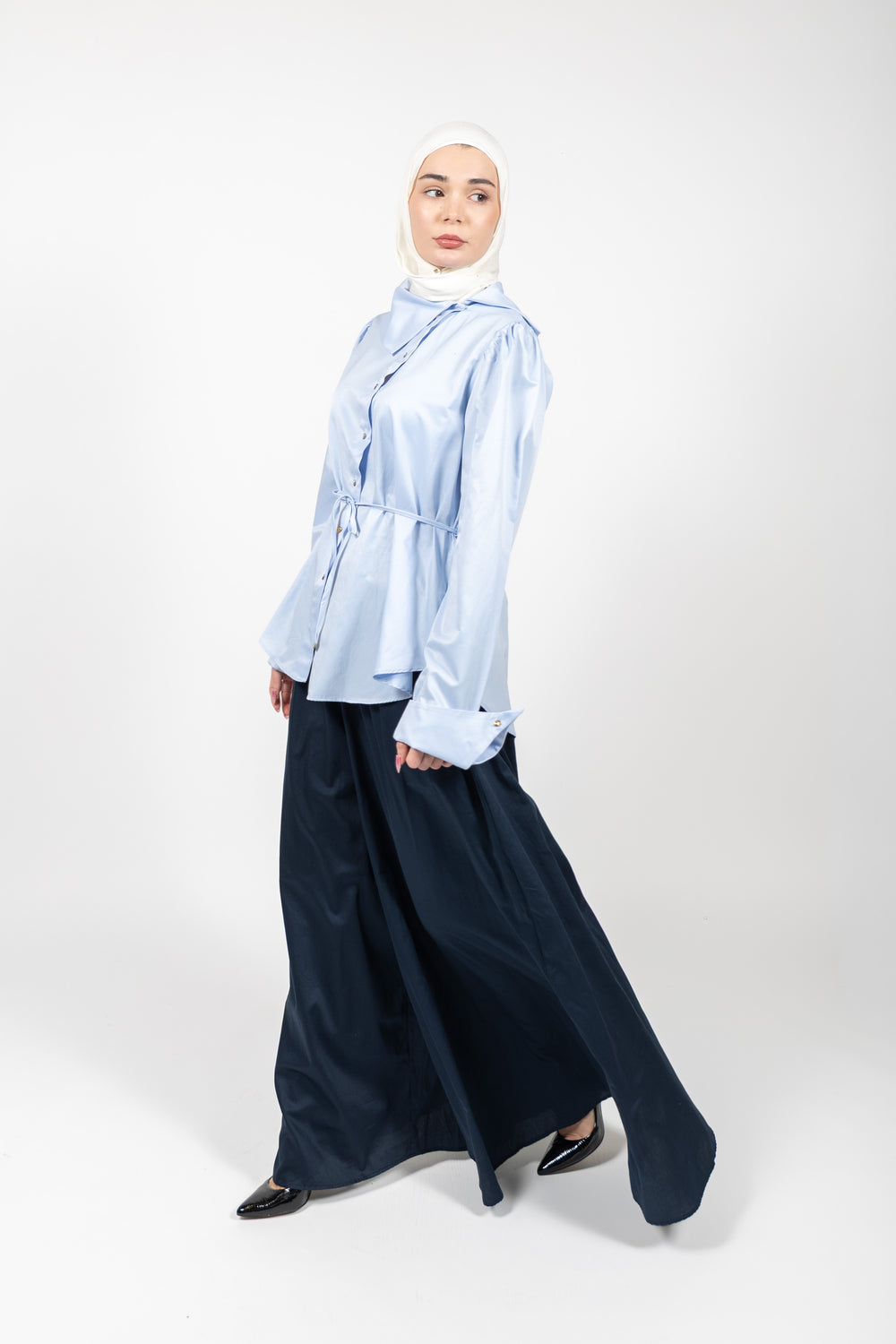 Woman wearing a light blue shirt and dark blue skirt on a white background