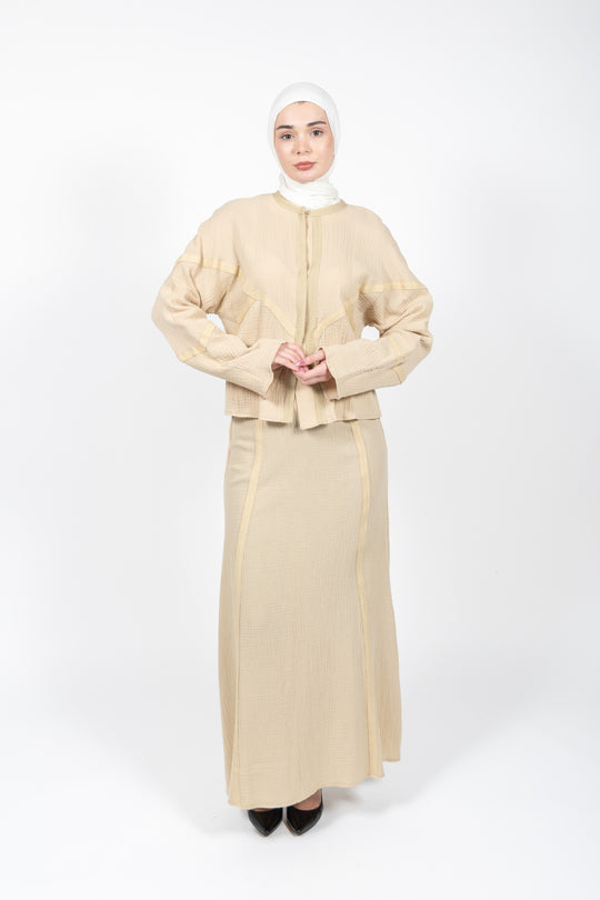 Woman wearing a beige outfit with a matching hijab on a white background