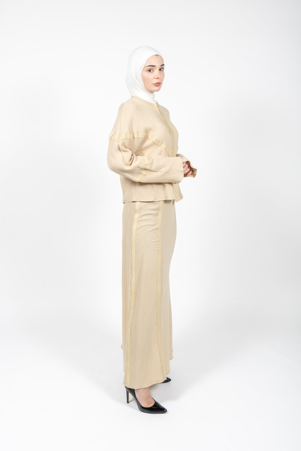 Woman wearing a beige outfit with a hijab on a white background