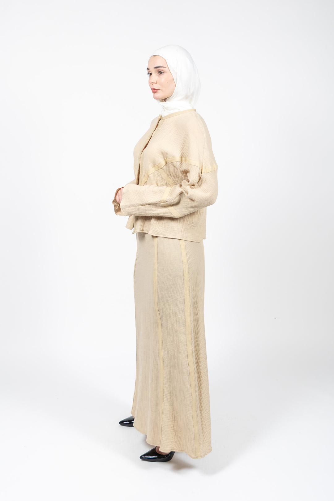Woman wearing a beige outfit with a hijab on a white background