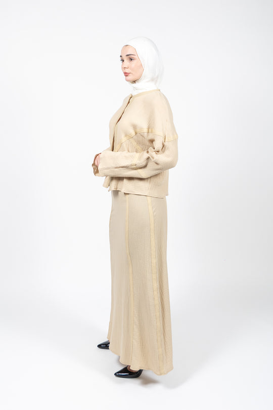 Woman wearing a beige outfit with a hijab on a white background