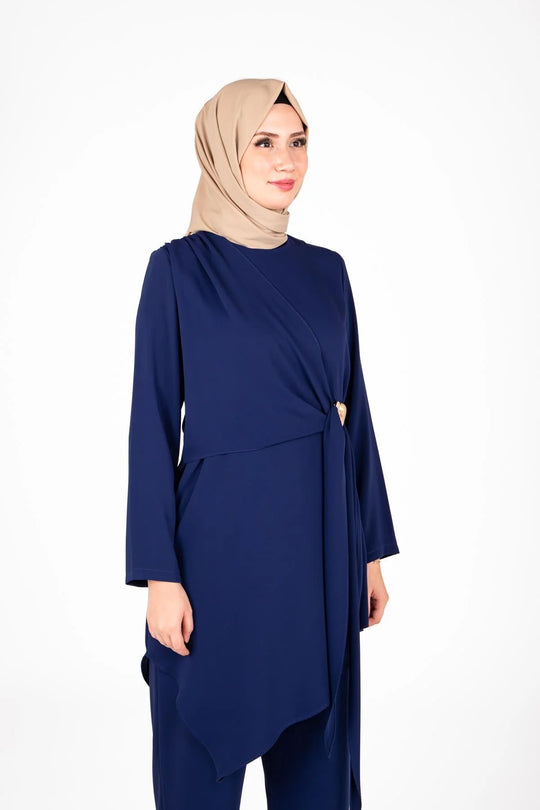 Woman wearing a navy blue outfit with a beige hijab on a white background
